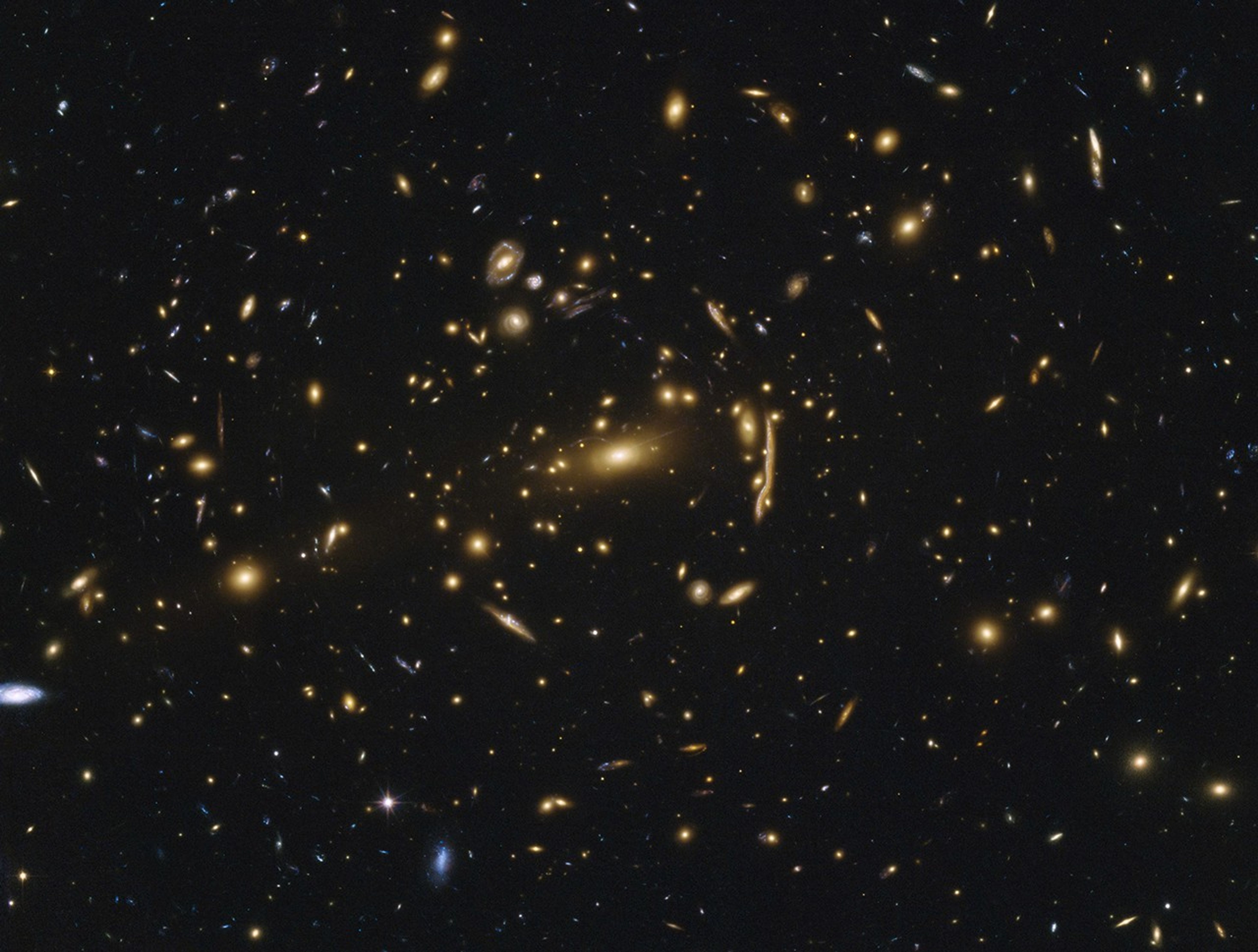 Large sample galaxies of different sizes and shapes, mostly a yellow-orange color, experiencing a lens-like distortion.